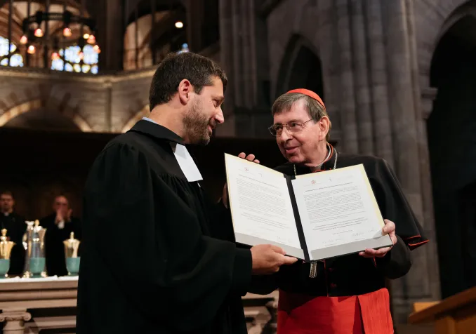 Gottfried Locher et le cardinal Kurt Koch tenant la déclaration d'intention proposant de commencer un dialogue officiel entre les protestants d'Europe et le Vatican. Elle a été signée à la cathédrale de Bâle le 16 septembre dernier. © FEPS/Olivier Hochstrasser